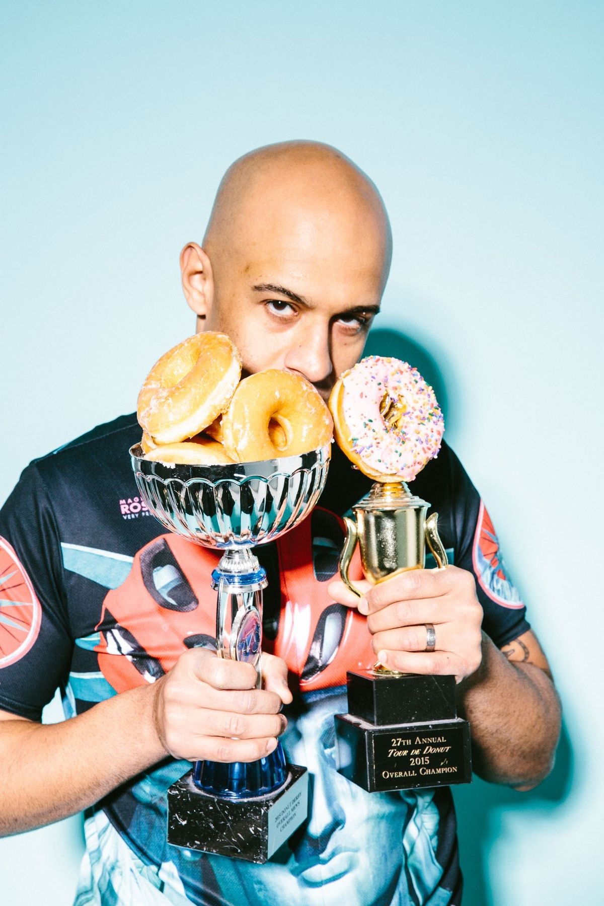 Yasir Salem holding two donut racing trophies piled with donuts