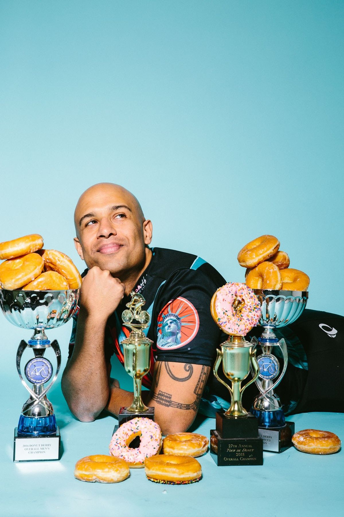 Yasir Salem lying behind a row of donut racing trophies and donuts