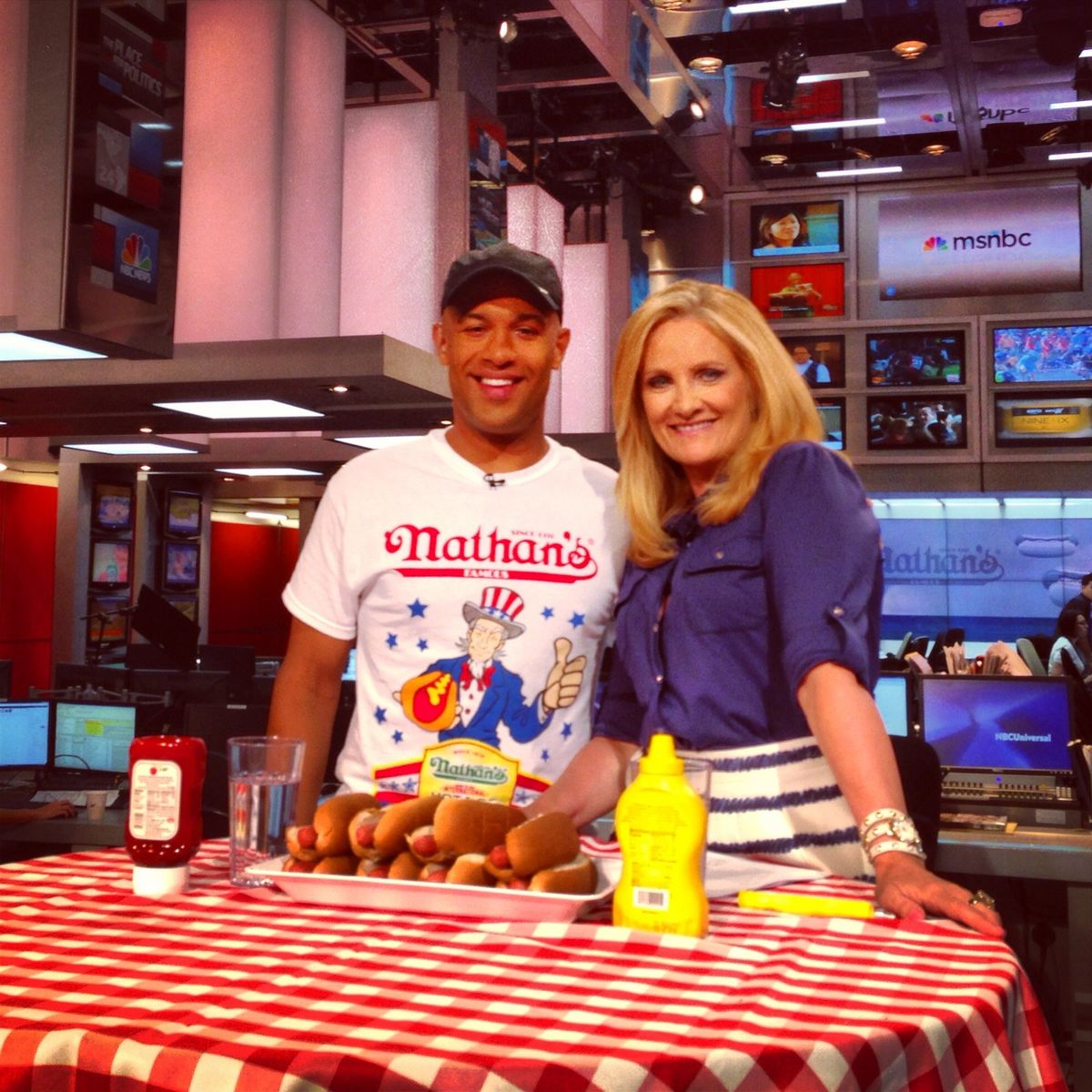 Yasir Salem with Alex Witt on the MSNBC set behind a table of hot dogs